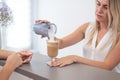 Receptionist in a beauty salon prepares coffee for a client.