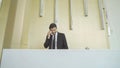 A receptionist or concierge man with uniform at front desk counter in lobby of hotel talking on the phone with guest about the Royalty Free Stock Photo