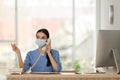 Receptionist with mask talking on phone at countertop in hospital Royalty Free Stock Photo