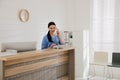 Receptionist talking on phone at countertop in hospital Royalty Free Stock Photo