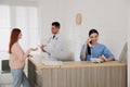 Receptionist talking on phone while doctor working with patient Royalty Free Stock Photo