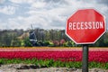 Recession stop sign with view of tulips field in Netherlands. Financial crash in world economy because of coronavirus pandemic.