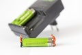 Rechargeable Battery with miniature worker over blurred charger on white background
