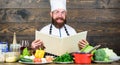 This recipe is just perfect. Man bearded hipster read book recipe near table fresh vegetables. Culinary arts. Recipe to Royalty Free Stock Photo