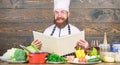 This recipe is just perfect. Man bearded hipster read book recipe near table fresh vegetables. Culinary arts. Recipe to Royalty Free Stock Photo