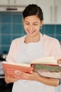 These recipes have been in the family for decades. a young woman reading a cook book. Royalty Free Stock Photo