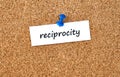 Reciprocity. Word written on a piece of paper, cork board background