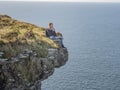 Reckless woman sitting on the edge of a cliff at the Irish west coast