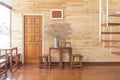 Reclaimed wooden wall with a wooden door, table sets and flowers in zinc vase in bright sunlight. Cozy and warm interior.