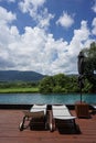 Recliner chairs on the deck next to swiming pool with green mountian background Royalty Free Stock Photo