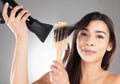 Recognise the wisdom in a hairstylist. Studio portrait of a beautiful young woman styling her hair against a grey Royalty Free Stock Photo