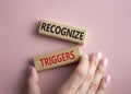 Recognize triggers symbol. Concept words Recognize triggers on wooden blocks. Businessman hand. Beautiful pink background.