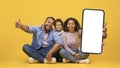 We Recommend. Smiling black family holding cell phone with white blank screen Royalty Free Stock Photo