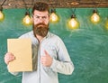 Recommendation concept. Bearded hipster holds book, chalkboard on background. Teacher in eyeglasses recommends book Royalty Free Stock Photo