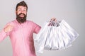 Recommendation concept. Guy shopping on sales season, pointing at bags. Hipster on smiling face recommends to buy. Man Royalty Free Stock Photo