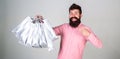 Recommendation concept. Hipster on happy face recommends to buy. Guy shopping and pointing at bags. Man with beard and Royalty Free Stock Photo