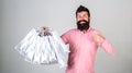 Recommendation concept. Hipster on smiling face recommends to buy. Guy shopping on sales season, pointing at bags. Man Royalty Free Stock Photo