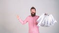 Recommendation concept. Hipster on smiling face recommends to buy. Man with beard and mustache carries bunch of shopping Royalty Free Stock Photo