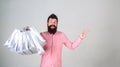 Recommendation concept. Hipster on smiling face recommends to buy. Man with beard and mustache carries bunch of shopping Royalty Free Stock Photo