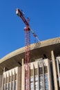 Reconstruction of a broken sports complex. The roof and facade of a large building, construction crane, vertical. Renovation