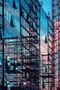 Reconstruction of modern office building with glass facade, construction site with scaffolding and crane forming abstract Royalty Free Stock Photo