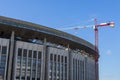 Reconstruction of an outdated sports complex. Ruined building facade and construction crane. Renovation, restoration of broken