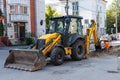 Reconstruction of underground sewerage system on city street in autumn. Bulldozer excavator digging deep ditch. Traffic