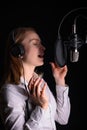 Recording female vocals. Young girl with a microphone and headphones in a recording studio. Recording vocals, blogger, reading