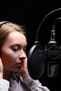 Recording female vocals. Young girl with a microphone and headphones in a recording studio. Recording vocals, blogger, reading