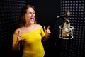 Recording vocals in a professional studio. Young woman sings in a recording studio, close-up. Professional microphone golden with