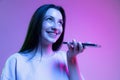 Half-length shot of emotional girl with long glossy dark hair isolated on purple background in neon light. Concept of Royalty Free Stock Photo