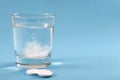 Recovering from a hangover and nursing a headache with aspirin concept with effervescent drink tablet dissolving in water with two Royalty Free Stock Photo