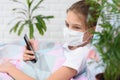 A recovering quarantined girl smiles and holds a mobile phone in her hands