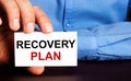 RECOVERY PLAN is written on a white business card in a man`s hand. Advertising concept Royalty Free Stock Photo