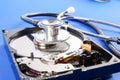 RECOVERY AND REPAIR TECHNOLOGY CONCEPT: Hard Disk Drive HDD with stethoscope isolated on a blue background. Royalty Free Stock Photo