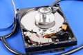 RECOVERY AND REPAIR TECHNOLOGY CONCEPT: Hard Disk Drive HDD with stethoscope isolated on a blue background. Royalty Free Stock Photo