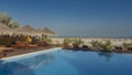 Recreation area on the ocean. Sunbeds and straw sun umbrellas stand by the swimming pool with blue water. Royalty Free Stock Photo