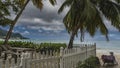 In the recreation area on a tropical beach, behind a white fence, there is a wooden table, benches