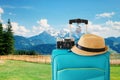 Recreation image of traveler luggage, camera and fedora hat in front of a rural landscape. holiday and vacation concept