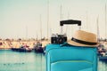 Recreation image of traveler luggage, camera and fedora hat infront of marina with yachts background. holiday and vacation concept