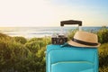 Recreation image of traveler luggage, camera and fedora hat infront of a rural lanscape. holiday and vacation concept