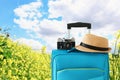 Recreation image of traveler luggage, camera and fedora hat infront of a rural lanscape. holiday and vacation concept