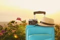 Recreation image of traveler luggage, camera and fedora hat infront of a rural lanscape. holiday and vacation concept