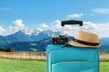 Recreation image of traveler luggage, camera and fedora hat infront of a rural lanscape. holiday and vacation concept