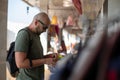 Recreation and travel. European male tourist in T-shirt with backpack and sunglasses chooses shoes at street market.