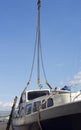 The boat being lifted by heavy industrial crane machinery against blue sky background Royalty Free Stock Photo