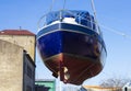 Recreational boat being lifted by heavy industrial crane machinery against blue sky background