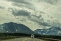 Recreational Vehicle driving on two lane blacktop highway toward mountains in Alaska range on rainy overcast misty day Royalty Free Stock Photo