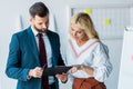 Recruiter and blonde woman looking at clipboard in office