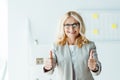 Recruiter in glasses showing thumbs up in office